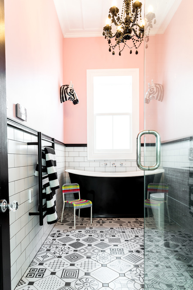 Inspiration for a mid-sized eclectic kids bathroom in Auckland with furniture-like cabinets, distressed cabinets, a freestanding tub, a corner shower, a one-piece toilet, black and white tile, porcelain tile, pink walls, porcelain floors, an undermount sink and granite benchtops.