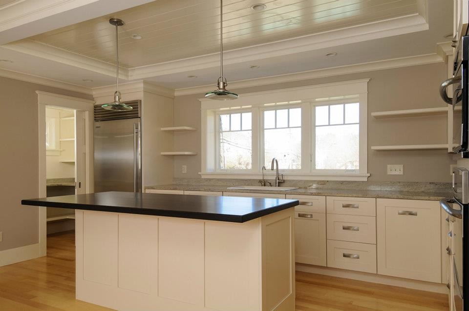 Photo of a mid-sized contemporary l-shaped kitchen in Boston with a drop-in sink, shaker cabinets, white cabinets, quartz benchtops, stainless steel appliances, light hardwood floors, with island and beige floor.