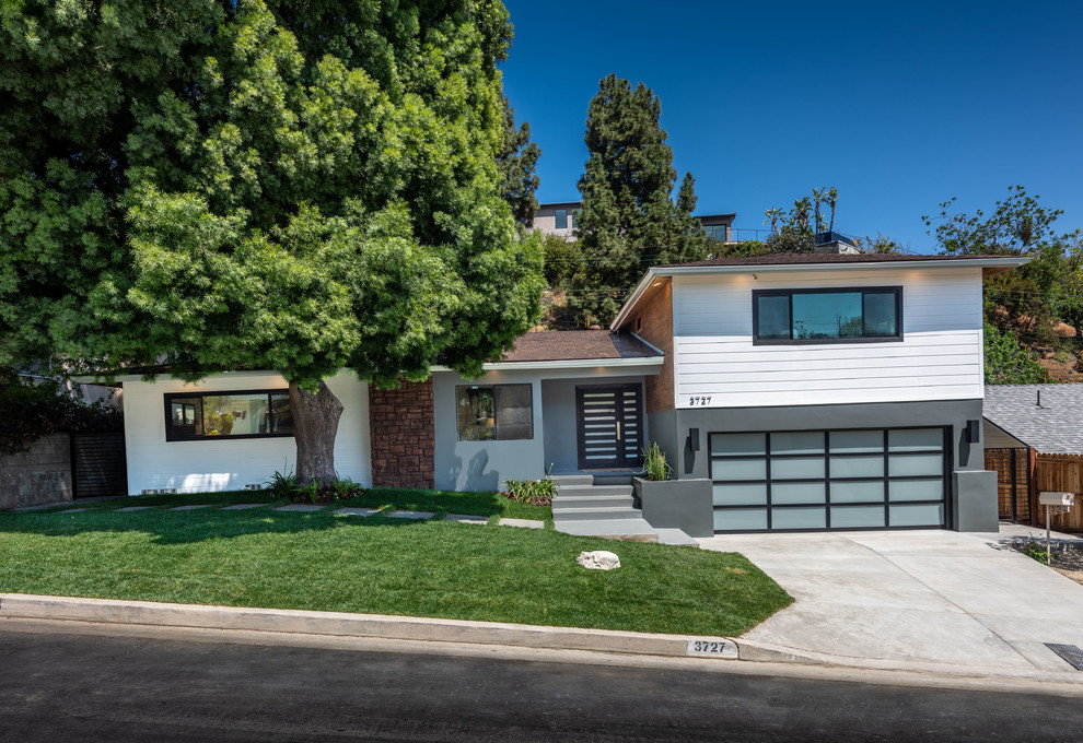 This is an example of an expansive midcentury two-storey grey house exterior in Los Angeles with wood siding, a hip roof and a shingle roof.