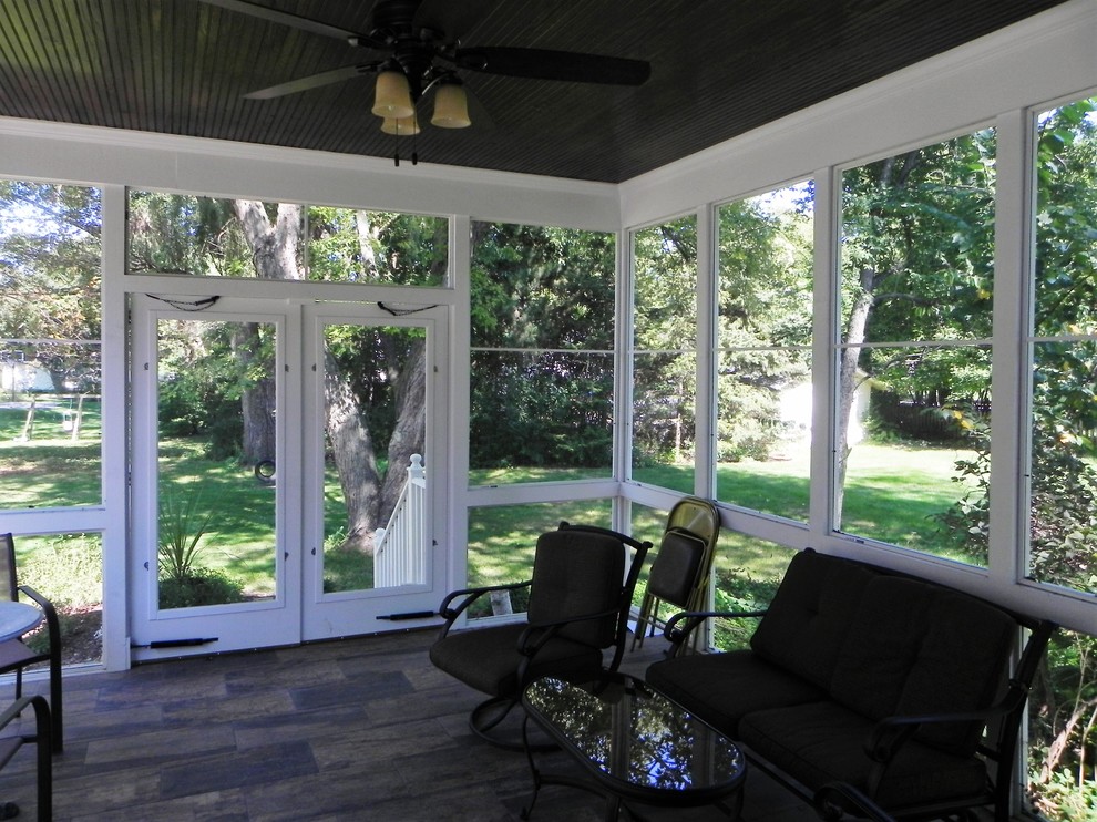 Traditional backyard screened-in verandah in Chicago with brick pavers and a roof extension.