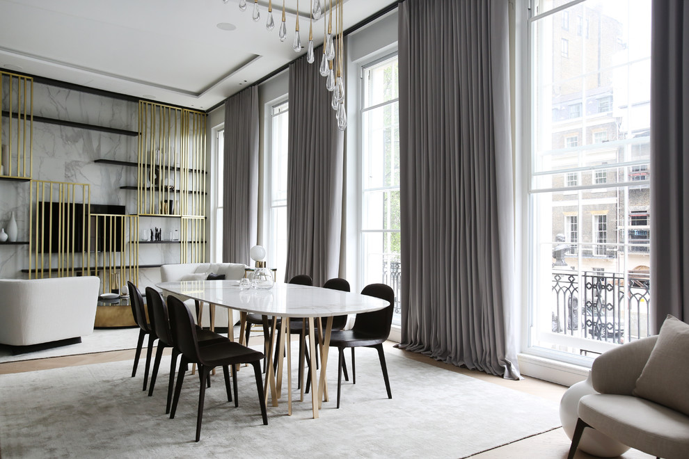 This is an example of a large contemporary open plan dining in London with light hardwood floors, no fireplace and beige walls.