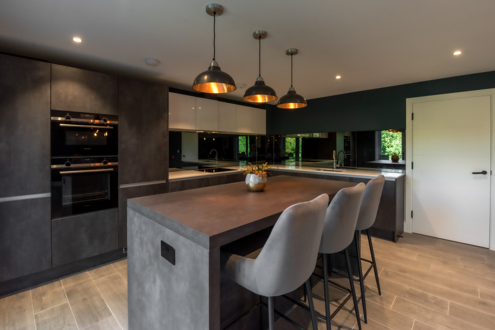 Inspiration for a mid-sized industrial laminate floor and gray floor open concept kitchen remodel in Kent with an integrated sink, gray cabinets, quartzite countertops, black backsplash, mirror backsplash, paneled appliances, an island and white countertops