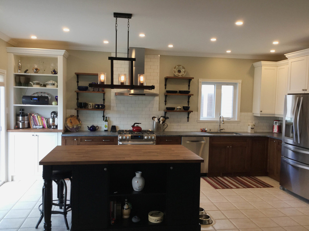 Inspiration for a mid-sized transitional l-shaped kitchen remodel in Ottawa with an undermount sink, shaker cabinets, dark wood cabinets, soapstone countertops, white backsplash, ceramic backsplash, stainless steel appliances and an island