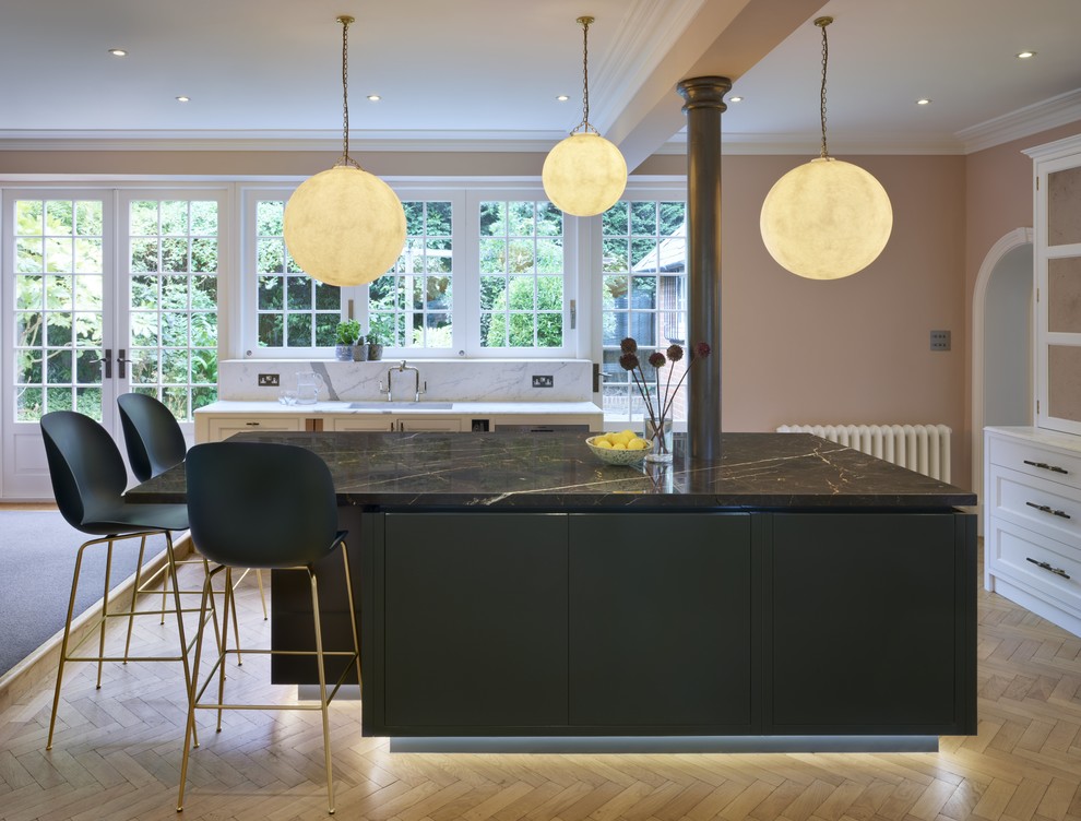 Mid-sized arts and crafts l-shaped open plan kitchen in London with flat-panel cabinets, marble benchtops, with island and brown benchtop.