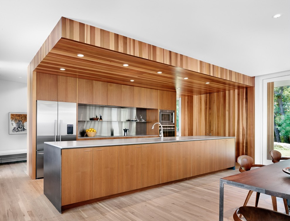 Contemporary galley eat-in kitchen in Austin with an undermount sink, flat-panel cabinets, medium wood cabinets, glass sheet splashback, stainless steel appliances, light hardwood floors and with island.