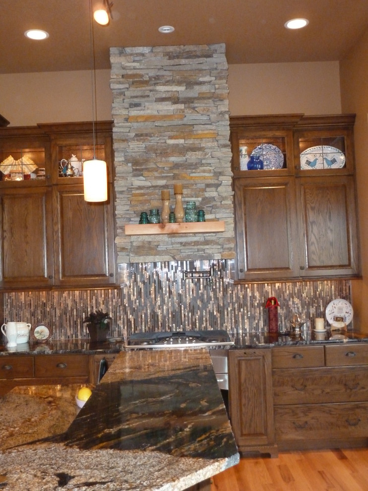 Example of a large mountain style l-shaped medium tone wood floor eat-in kitchen design with an undermount sink, raised-panel cabinets, dark wood cabinets, granite countertops, multicolored backsplash, matchstick tile backsplash, stainless steel appliances and an island