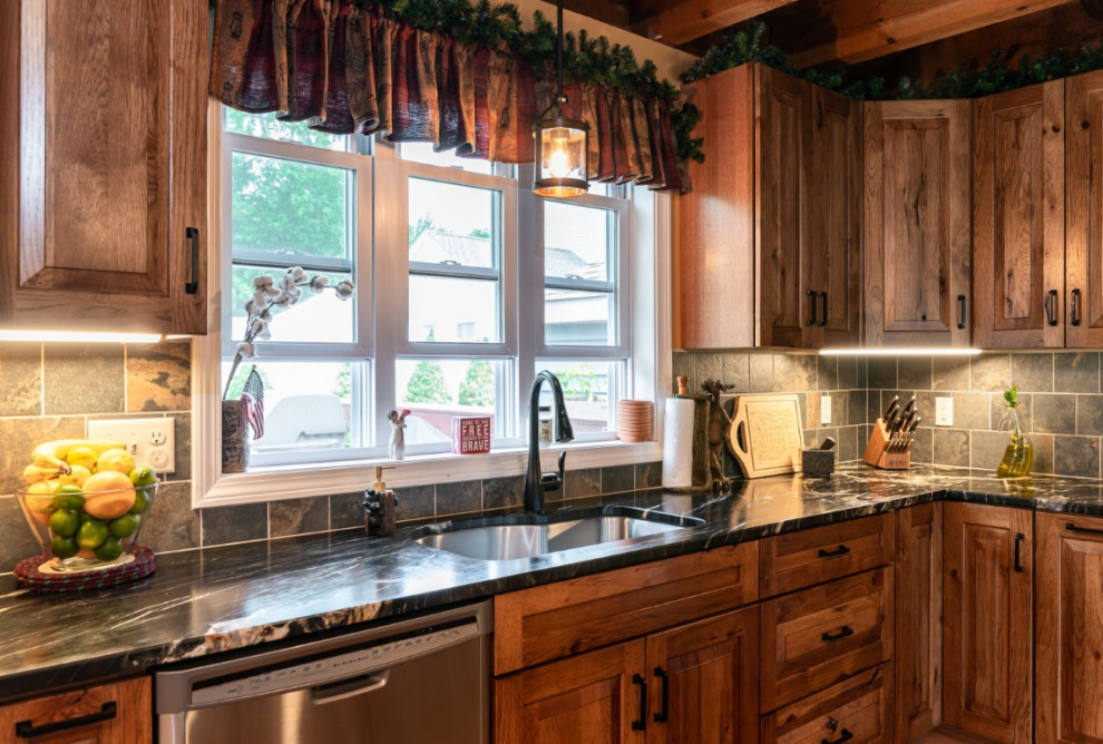 Example of a mountain style l-shaped medium tone wood floor kitchen design in Boston with an undermount sink, raised-panel cabinets, medium tone wood cabinets, granite countertops, gray backsplash, stainless steel appliances, an island and black countertops
