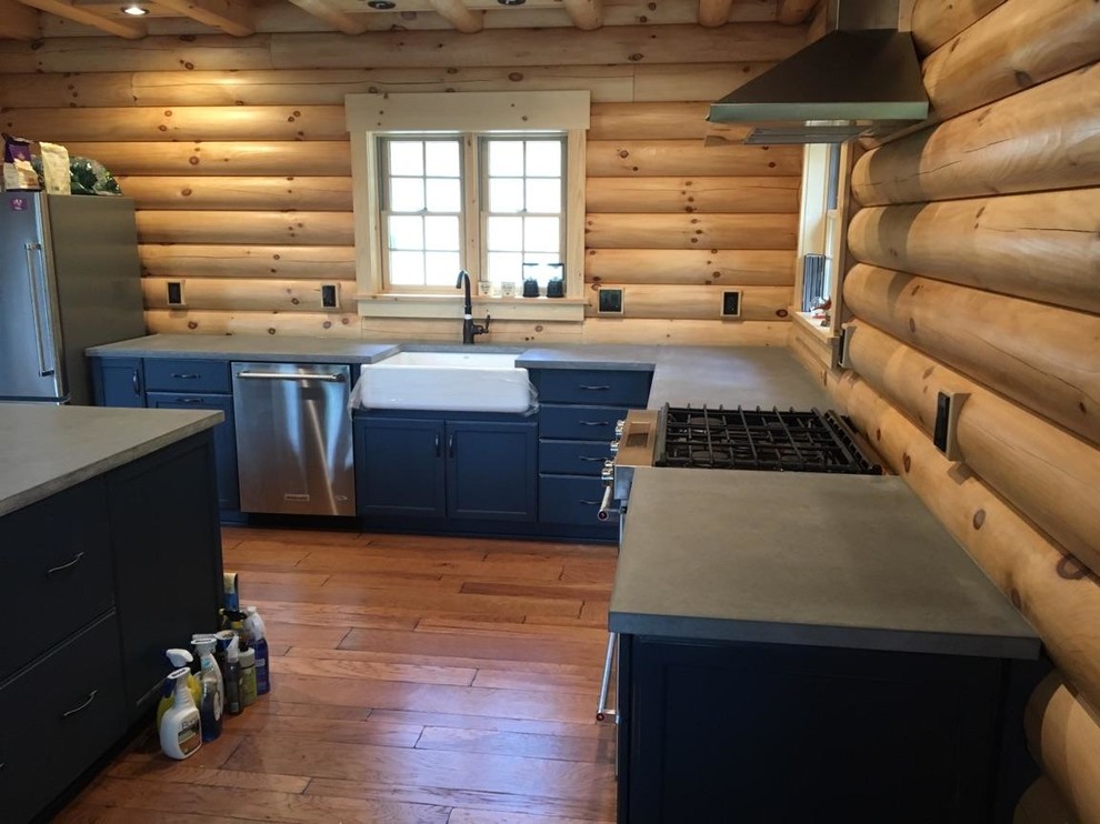 This is an example of an industrial l-shaped eat-in kitchen in New York with blue cabinets, concrete benchtops and with island.