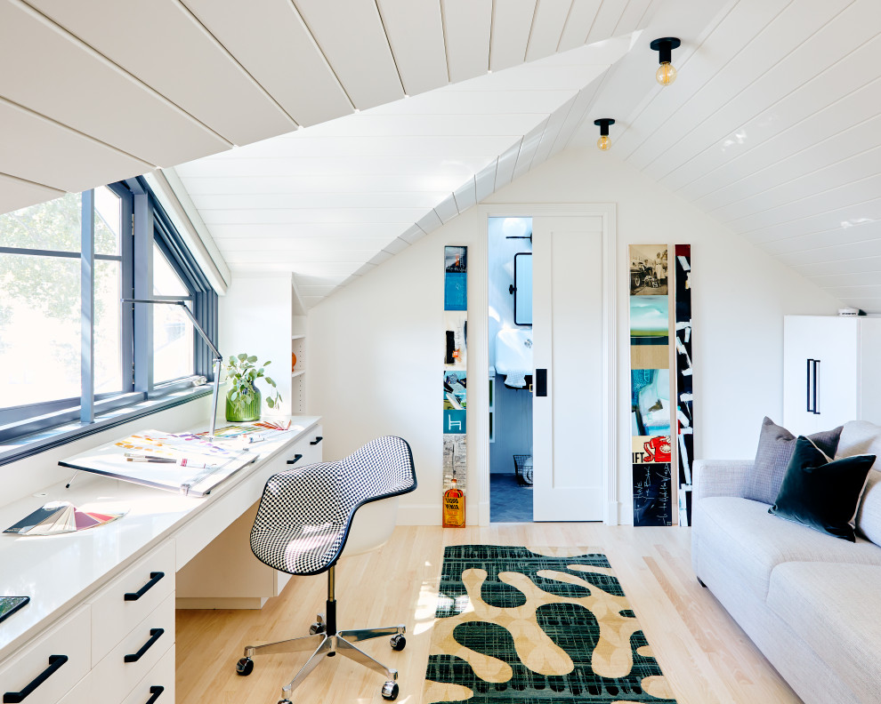 This is an example of a contemporary home office in San Francisco with white walls, light hardwood floors, a built-in desk, vaulted, timber and beige floor.