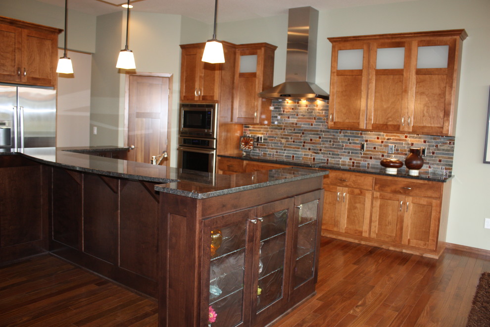 Mid-sized transitional l-shaped medium tone wood floor kitchen photo with medium tone wood cabinets, granite countertops, multicolored backsplash, mosaic tile backsplash, stainless steel appliances, an island and recessed-panel cabinets