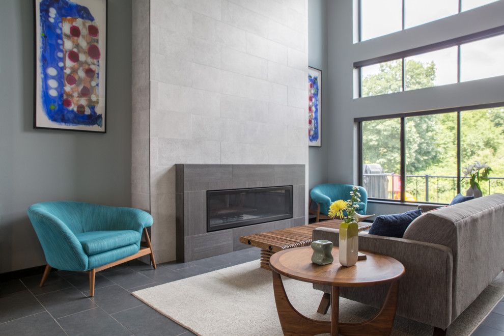 Cette photo montre un salon moderne de taille moyenne et fermé avec un mur gris, une cheminée standard, un sol gris, un sol en ardoise et un manteau de cheminée en pierre.
