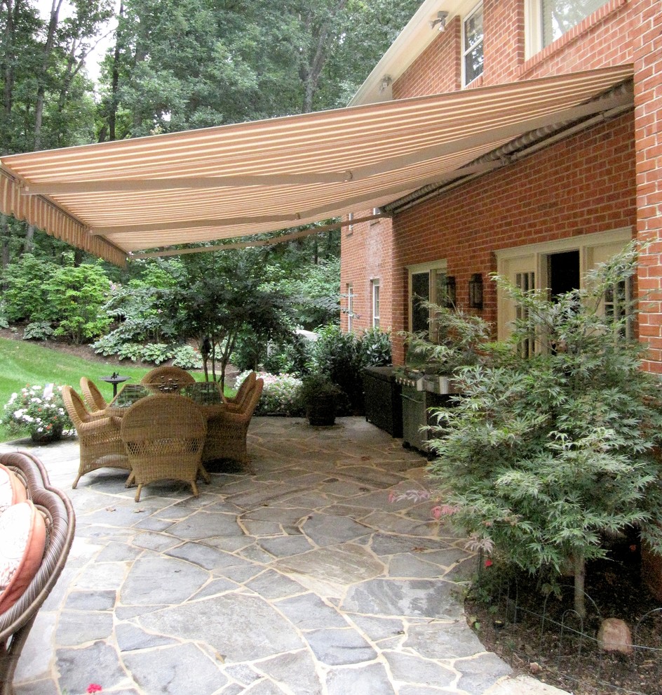 Photo of a large traditional backyard patio in DC Metro with a fire feature, natural stone pavers and an awning.