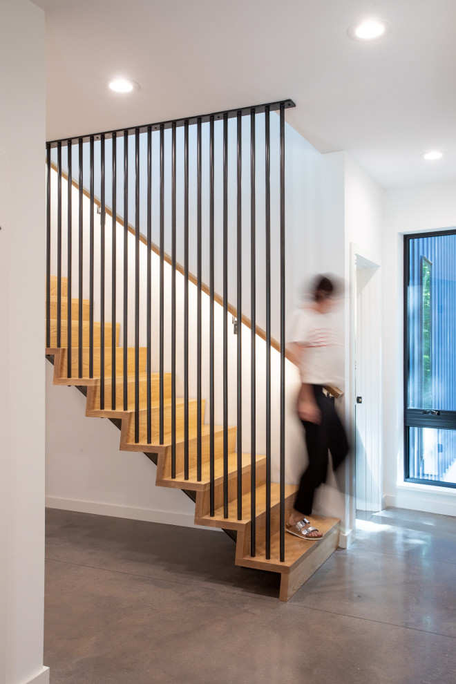Inspiration pour un grand escalier flottant design avec des marches en bois, des contremarches en bois et un garde-corps en métal.