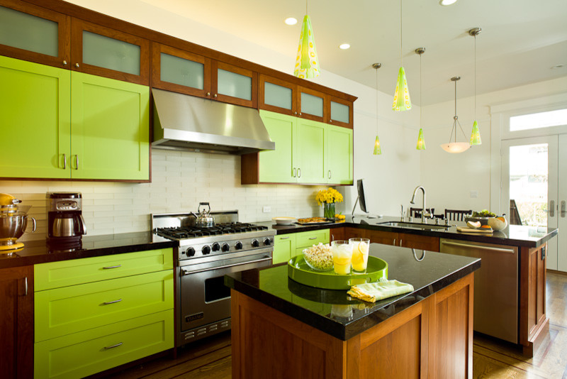 Photo of a mid-sized arts and crafts u-shaped eat-in kitchen in Nashville with green cabinets, an undermount sink, white splashback, subway tile splashback, stainless steel appliances, with island, flat-panel cabinets, light hardwood floors, brown floor and black benchtop.