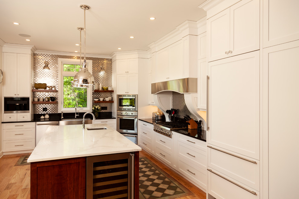 Mid-sized transitional l-shaped enclosed kitchen photo with shaker cabinets, white cabinets, stainless steel appliances, an island and white countertops