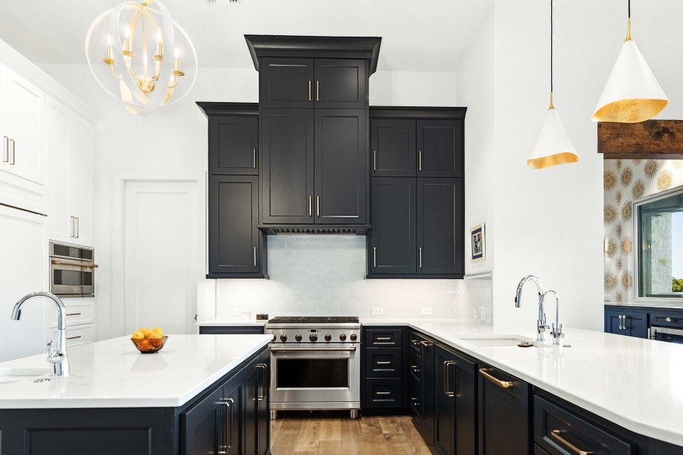 Large classic u-shaped kitchen/diner in Austin with a submerged sink, recessed-panel cabinets, blue cabinets, white splashback, stainless steel appliances, medium hardwood flooring, an island, brown floors and white worktops.