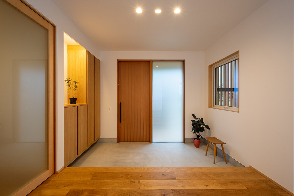Großer Eingang mit Korridor, weißer Wandfarbe, braunem Holzboden, Schiebetür, hellbrauner Holzhaustür, braunem Boden, Tapetendecke und Tapetenwänden in Sonstige