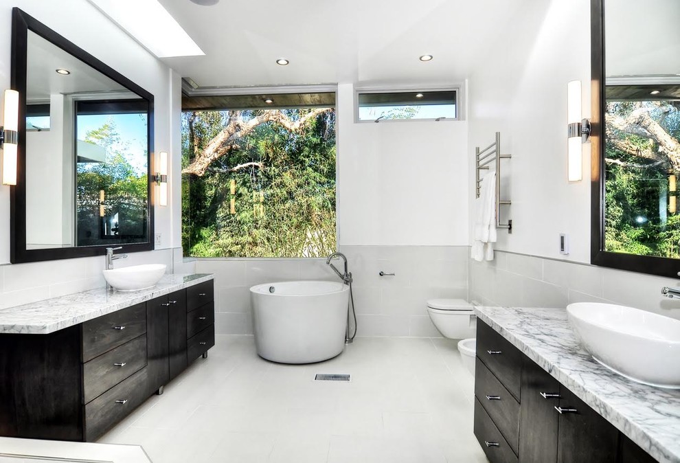 Mid-sized contemporary master bathroom in Orange County with flat-panel cabinets, black cabinets, a japanese tub, an open shower, a wall-mount toilet, gray tile, porcelain tile, white walls, porcelain floors, a vessel sink and marble benchtops.