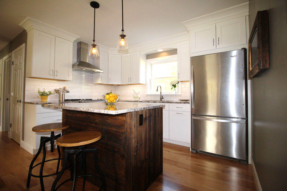 Mid-sized transitional l-shaped light wood floor eat-in kitchen photo in Burlington with a single-bowl sink, shaker cabinets, white cabinets, granite countertops, white backsplash, ceramic backsplash, stainless steel appliances and an island
