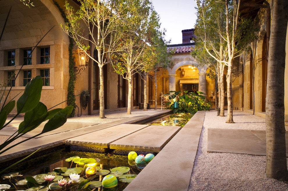 Mediterranean front yard patio in Dallas with a water feature and natural stone pavers.