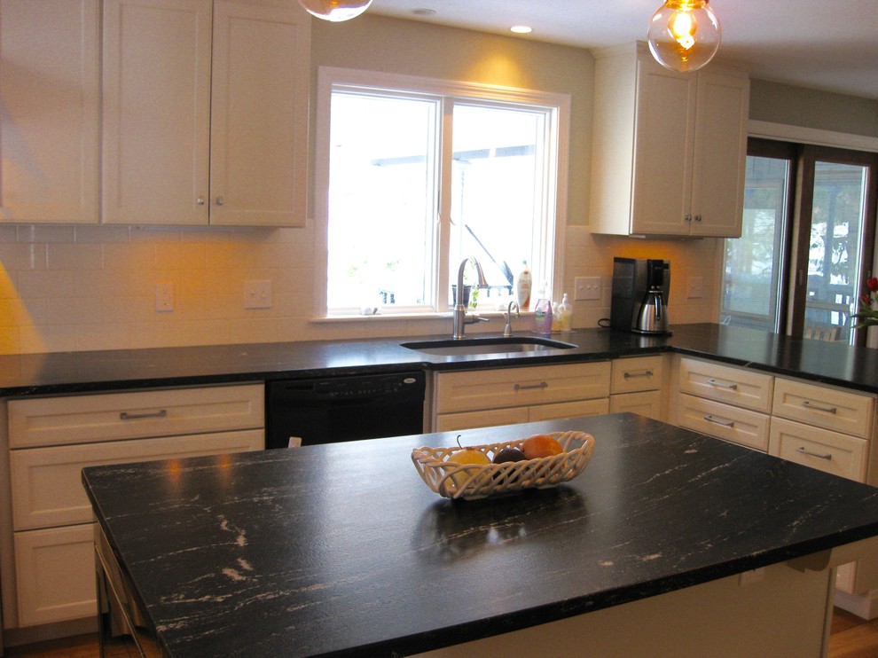 Example of a transitional l-shaped medium tone wood floor eat-in kitchen design in Boston with an undermount sink, shaker cabinets, white cabinets, quartz countertops, white backsplash, ceramic backsplash, stainless steel appliances, an island and black countertops
