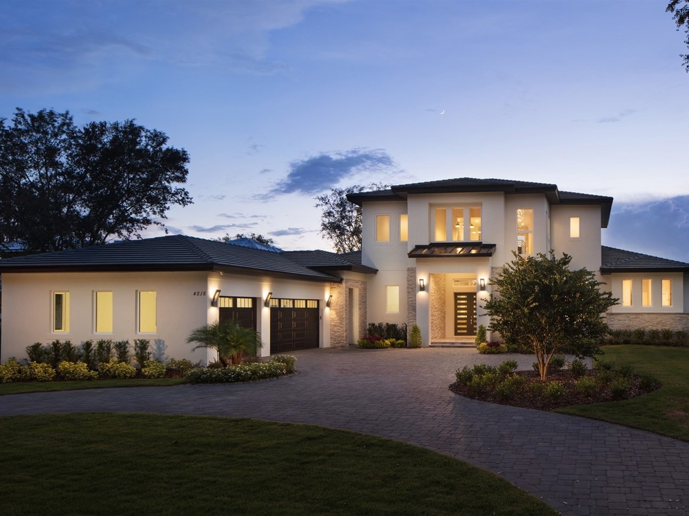 Design ideas for a large modern two-storey stucco white house exterior in Orlando with a gable roof and a tile roof.