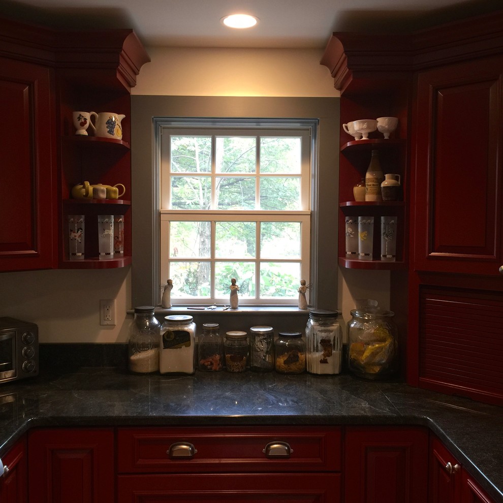 Large country u-shaped kitchen in Boston with a farmhouse sink, raised-panel cabinets, red cabinets, solid surface benchtops, stainless steel appliances, light hardwood floors and with island.