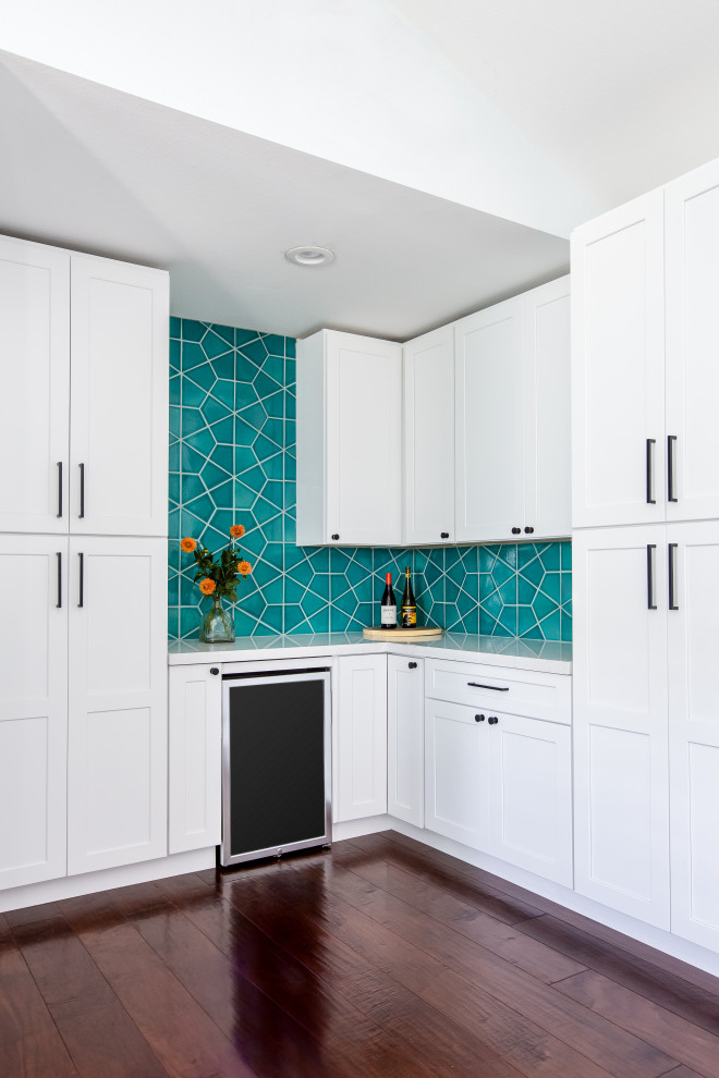 Design ideas for a mid-sized eclectic l-shaped wet bar in San Diego with white cabinets, blue splashback, ceramic splashback, dark hardwood floors, brown floor and white benchtop.