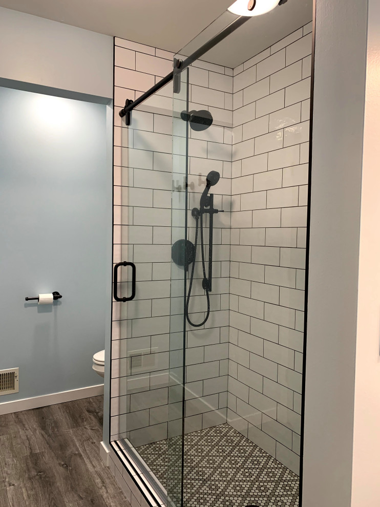 Bild på ett litet industriellt vit vitt en-suite badrum, med skåp i mellenmörkt trä, en kantlös dusch, svart och vit kakel, blå väggar, vinylgolv, ett integrerad handfat, bänkskiva i kvarts, brunt golv och dusch med skjutdörr