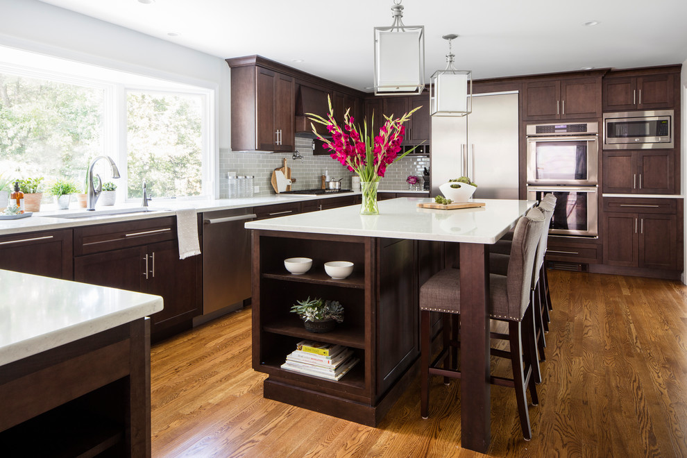 Photo of a transitional kitchen in Boston with an undermount sink, shaker cabinets, brown cabinets, grey splashback, subway tile splashback, stainless steel appliances, medium hardwood floors, with island and brown floor.