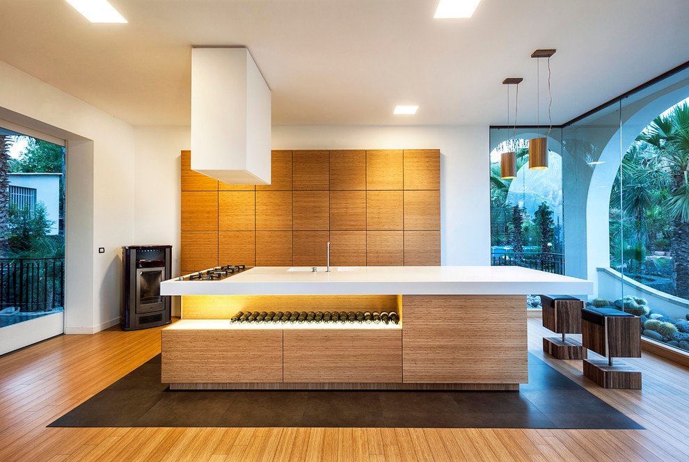 Large contemporary single-wall open plan kitchen in Catania-Palermo with an integrated sink, flat-panel cabinets, light wood cabinets, solid surface benchtops, light hardwood floors and with island.