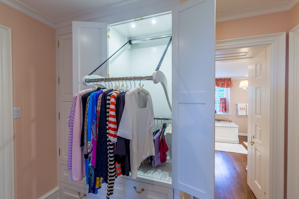 This is an example of a large traditional women's dressing room in Philadelphia with white cabinets and carpet.