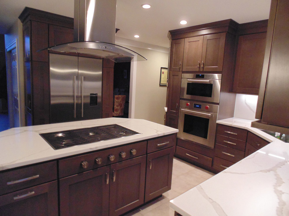 This is an example of a mid-sized transitional u-shaped eat-in kitchen in New York with an undermount sink, recessed-panel cabinets, dark wood cabinets, quartz benchtops, beige splashback, stainless steel appliances, ceramic floors, with island, beige floor and beige benchtop.