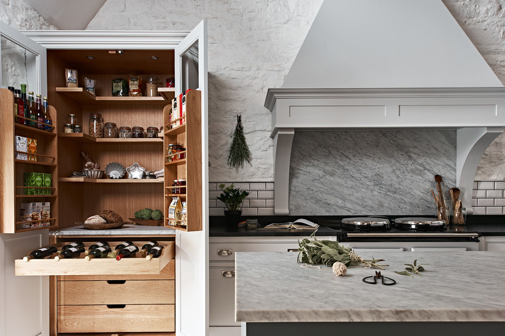 Design ideas for a large country l-shaped separate kitchen in Wiltshire with recessed-panel cabinets, white cabinets, marble benchtops, grey splashback, marble splashback, travertine floors, with island and beige floor.