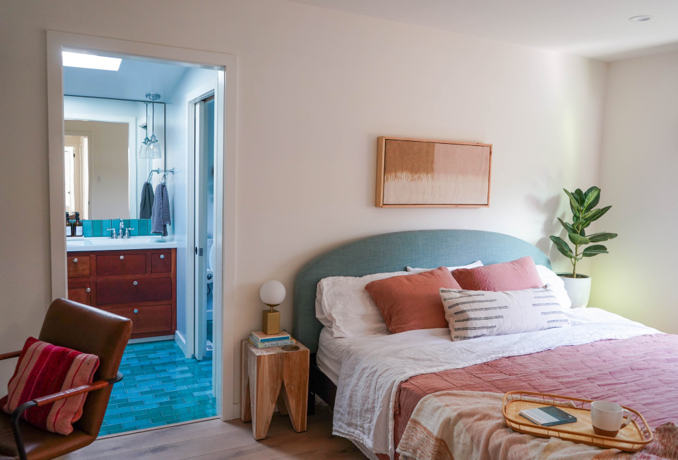 Modelo de dormitorio costero grande con paredes blancas y suelo de madera clara