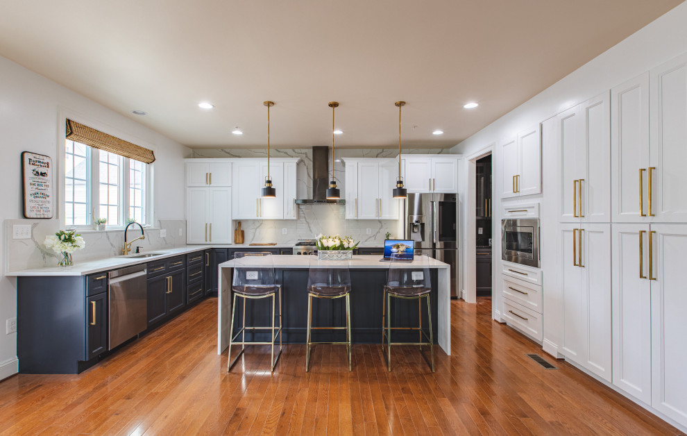 Inspiration for a transitional medium tone wood floor and brown floor kitchen remodel in Baltimore with an undermount sink, recessed-panel cabinets, white cabinets, white backsplash, stainless steel appliances, an island and white countertops