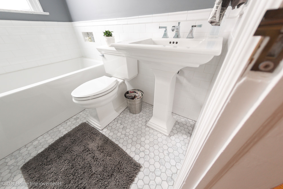 Photo of a small contemporary bathroom in New York with an alcove tub, an alcove shower, a two-piece toilet, white tile, porcelain tile, grey walls, marble floors, a pedestal sink, multi-coloured floor and a hinged shower door.