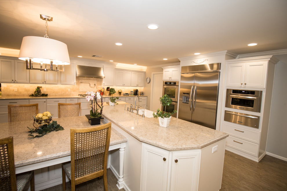 Huge transitional open concept kitchen photo with a farmhouse sink, recessed-panel cabinets, white cabinets, quartz countertops, beige backsplash, stone tile backsplash, stainless steel appliances and an island