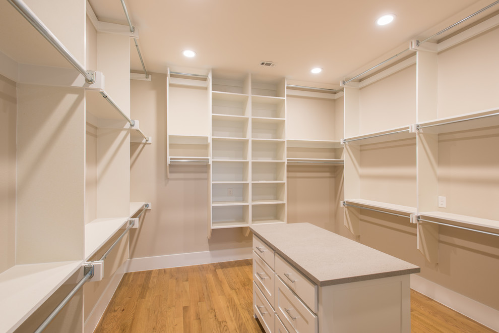 This is an example of a large transitional gender-neutral walk-in wardrobe in Dallas with shaker cabinets, white cabinets and light hardwood floors.