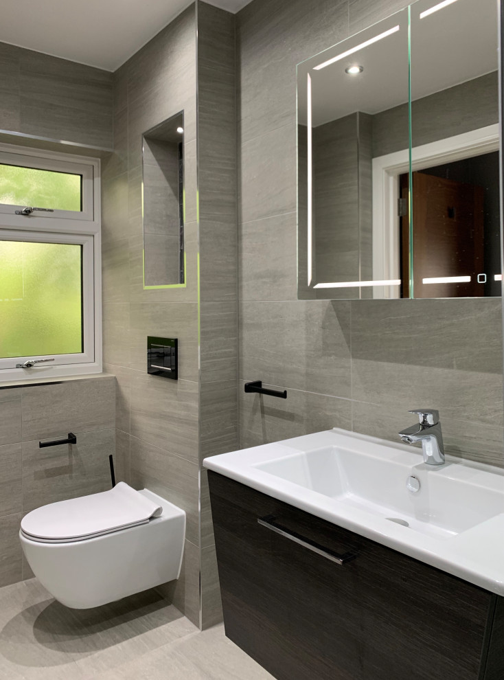 Inspiration för mellanstora moderna en-suite badrum, med släta luckor, grå skåp, en öppen dusch, en vägghängd toalettstol, grå kakel, porslinskakel, grå väggar, klinkergolv i porslin, ett väggmonterat handfat, grått golv och med dusch som är öppen