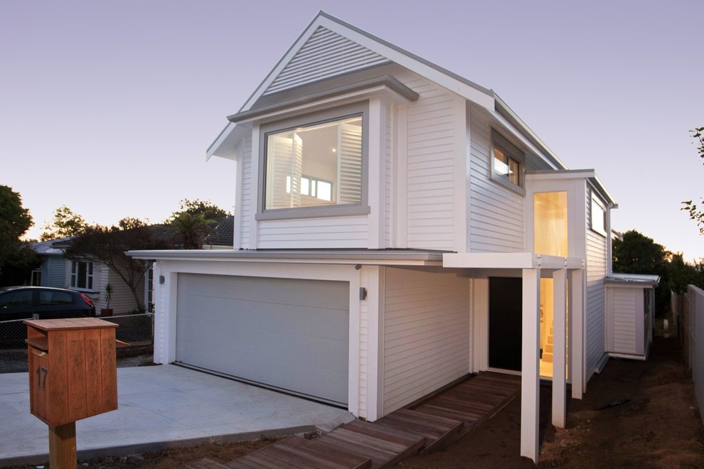 Design ideas for a mid-sized beach style two-storey white exterior in Auckland with wood siding and a gable roof.