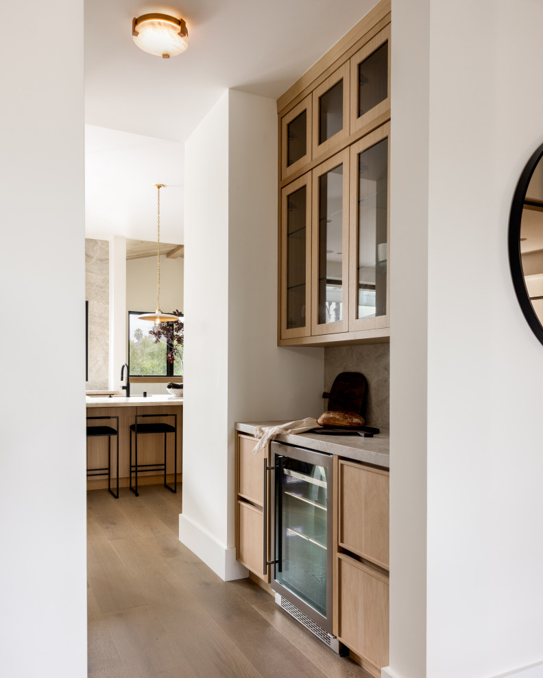 Example of a light wood floor and beige floor home bar design in Los Angeles with flat-panel cabinets, beige cabinets, quartzite countertops and beige countertops