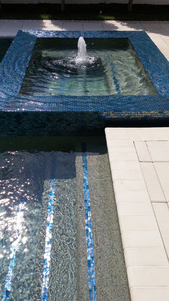 Inspiration for a modern backyard rectangular pool in Orlando with a water feature and concrete pavers.