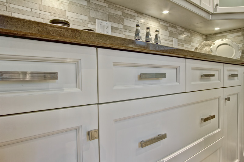 Mid-sized transitional u-shaped separate kitchen in Toronto with an undermount sink, recessed-panel cabinets, white cabinets, quartz benchtops, beige splashback, subway tile splashback, stainless steel appliances, porcelain floors and no island.