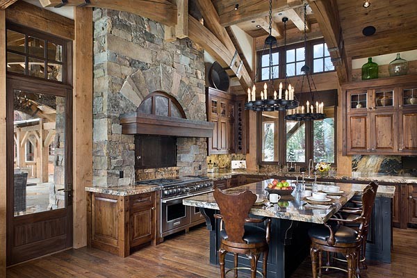 Example of a mountain style light wood floor eat-in kitchen design with stainless steel appliances, an island, beaded inset cabinets and brown cabinets