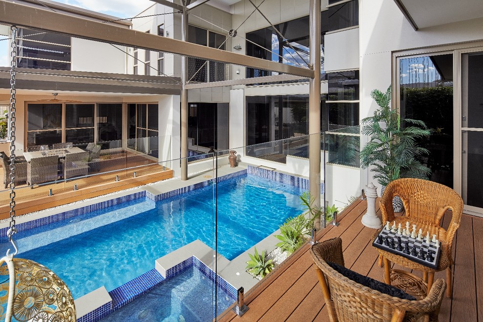 Large beach style backyard custom-shaped lap pool in Sydney with a hot tub and concrete pavers.
