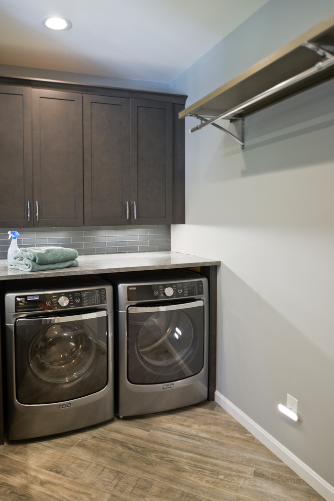 Design ideas for a mid-sized modern l-shaped utility room in DC Metro with an undermount sink, flat-panel cabinets, black cabinets, quartzite benchtops, grey walls, a side-by-side washer and dryer and grey floor.