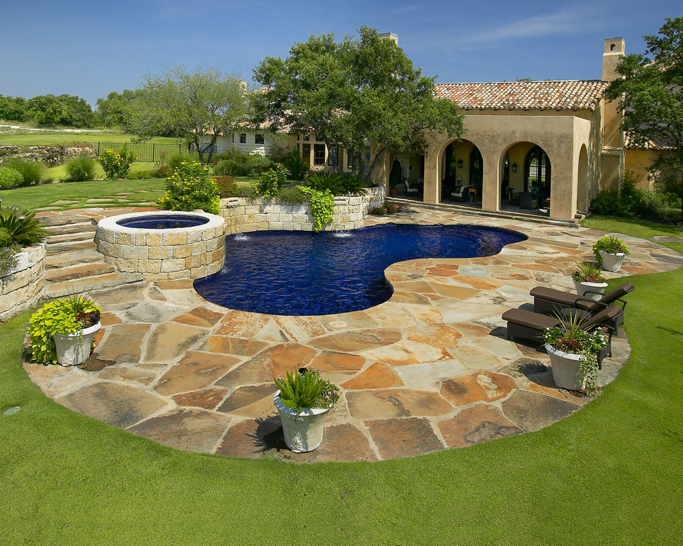 Photo of an expansive mediterranean backyard custom-shaped natural pool in Austin with a hot tub.