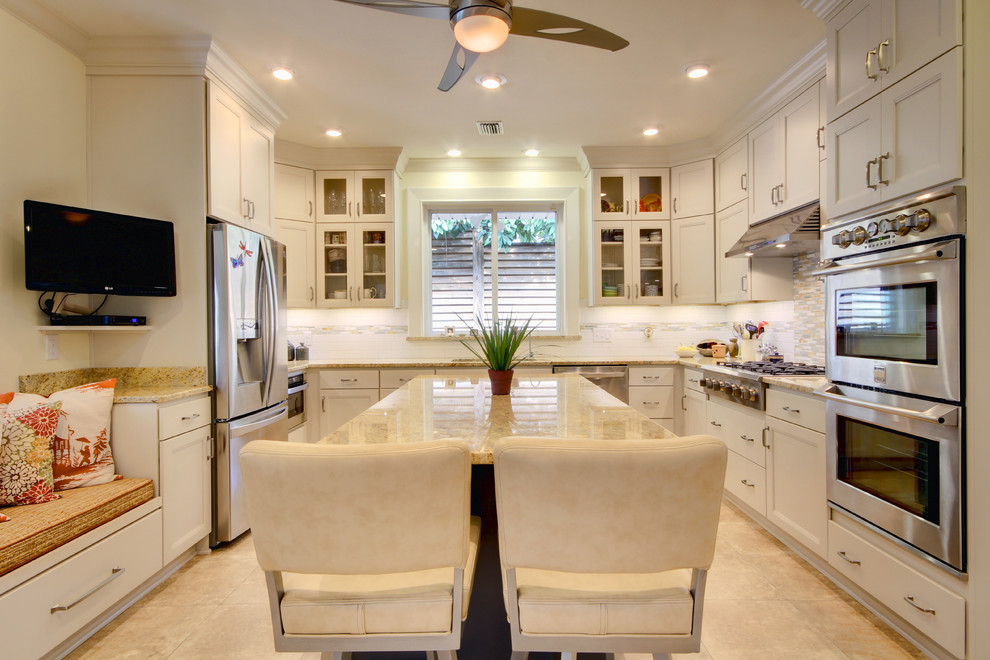 Example of a transitional u-shaped eat-in kitchen design in Miami with a farmhouse sink, recessed-panel cabinets, white cabinets, granite countertops, multicolored backsplash, subway tile backsplash and stainless steel appliances