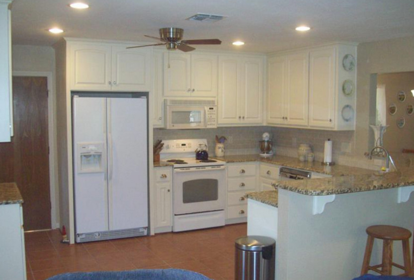 Kitchen - ceramic tile kitchen idea in Austin with white cabinets, granite countertops and white appliances